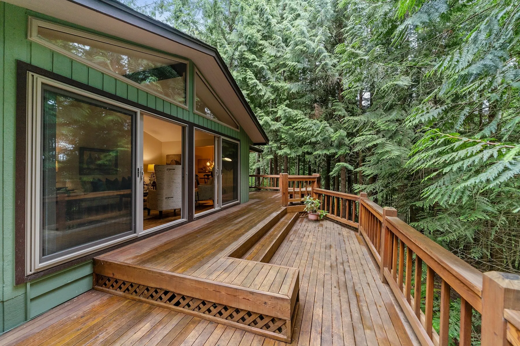 A wooden deck running alongside large residential windows